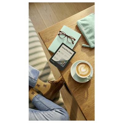 Vogelperspektive einer Person, die sich an einem Holztisch entspannt, mit einem Telefon, einer Brille, einem Kaffee, einem gefalteten Handtuch und Stiefeln, was eine gemütliche Morgenauszeit andeutet.