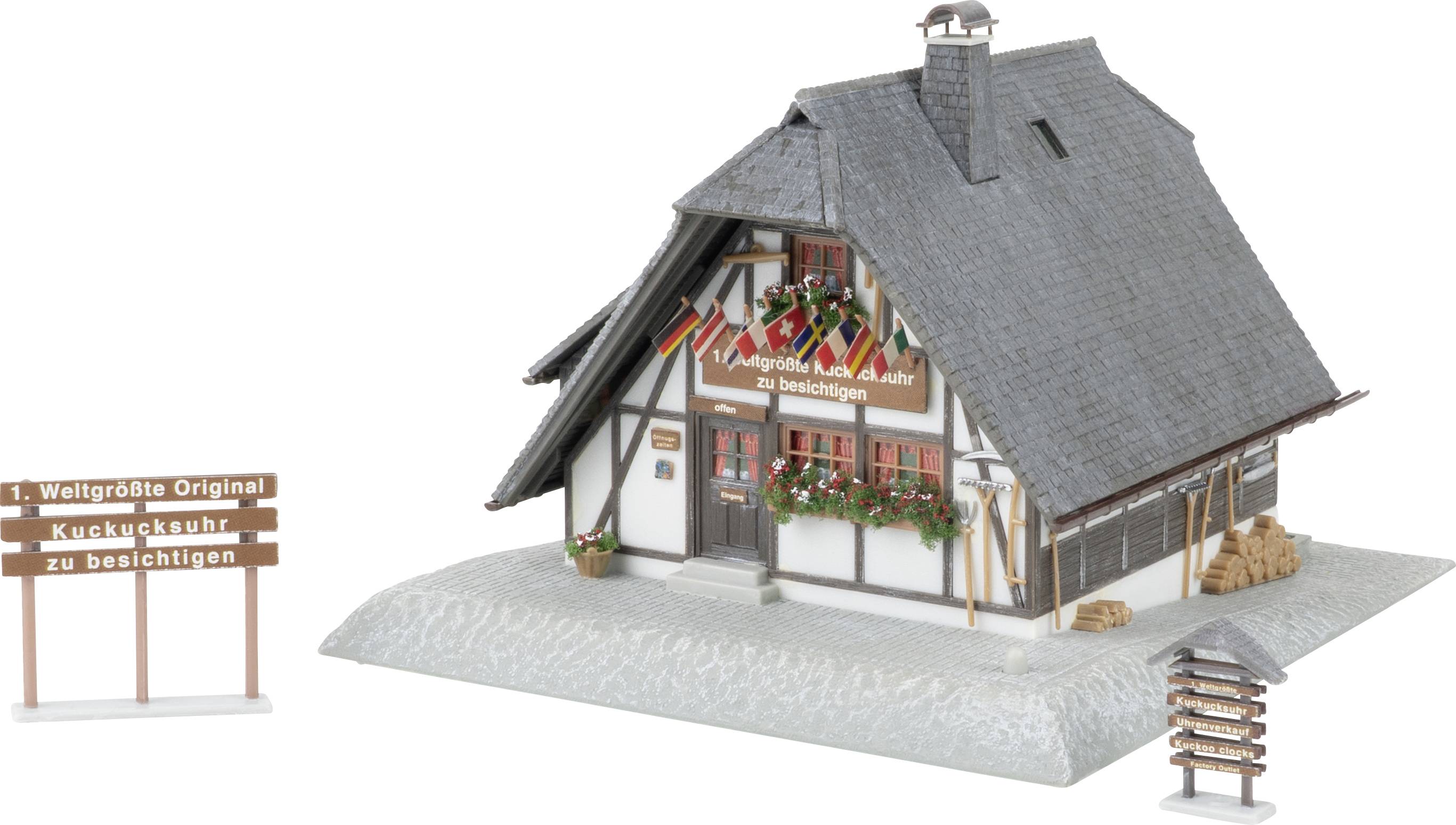 Modell eines kleinen Fachwerkhauses mit steilem Dach, Blumenkästen und Schildern mit den Aufschriften „1. Weltgrößte Original Kuckucksuhr zu besichtigen" und „2. hier auch zu besichtigen".
