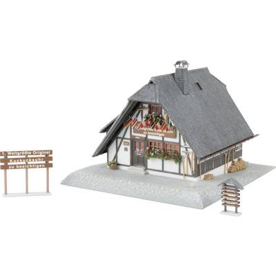 Modell eines kleinen Fachwerkhauses mit steilem Dach, Blumenkästen und Schildern mit den Aufschriften „1. Weltgrößte Original Kuckucksuhr zu besichtigen" und „2. hier auch zu besichtigen".