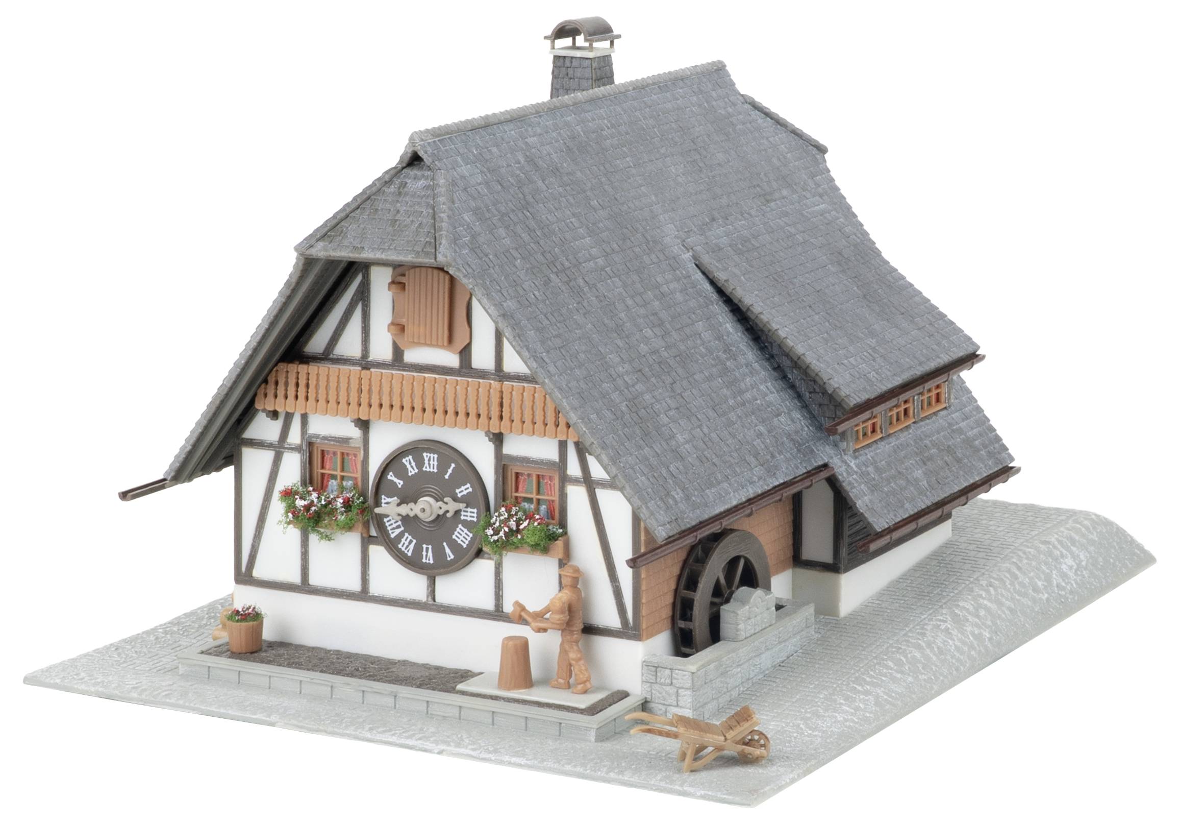 Modell eines rustikalen Chalethaus mit einer großen Uhr an der Fassade, Blumenkästen, einem Schornstein und kleinen Figuren auf der Veranda.