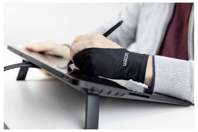 Eine Person, die einen Wacom-Zeichenhandschuh trägt, benutzt einen Stylus auf einem Tablet-Computer auf einem Ständer.