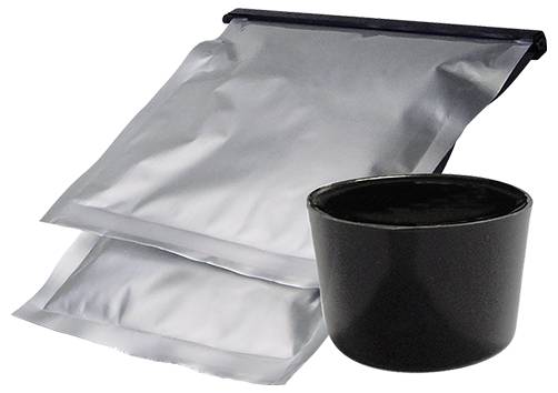 Silberner wiederverschließbarer Beutel, der hinter einer kleinen schwarzen Tasse auf weißem Hintergrund steht.