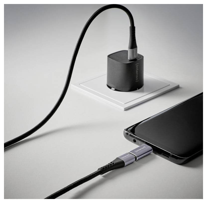 Ein Smartphone ist über ein Kabel mit einem kleinen LadeHub auf einem Schreibtisch verbunden und zeigt eine Ladeeinrichtung.