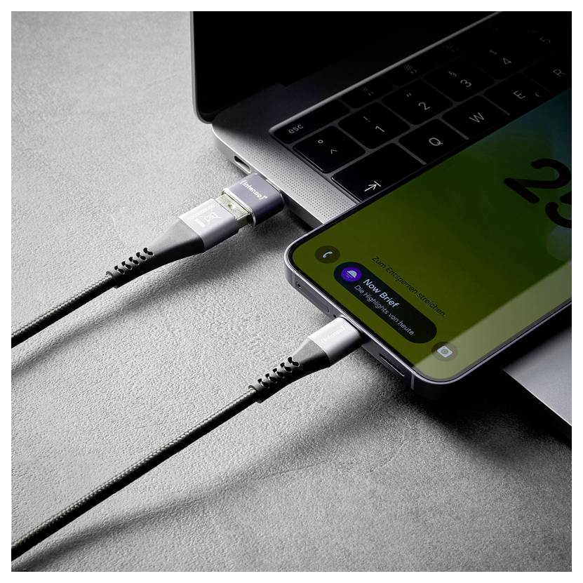 Zwei Smartphones sind über Ladekabel mit einem Laptop verbunden, was auf ein Aufladen von Geräten oder Datentransfer hindeutet.