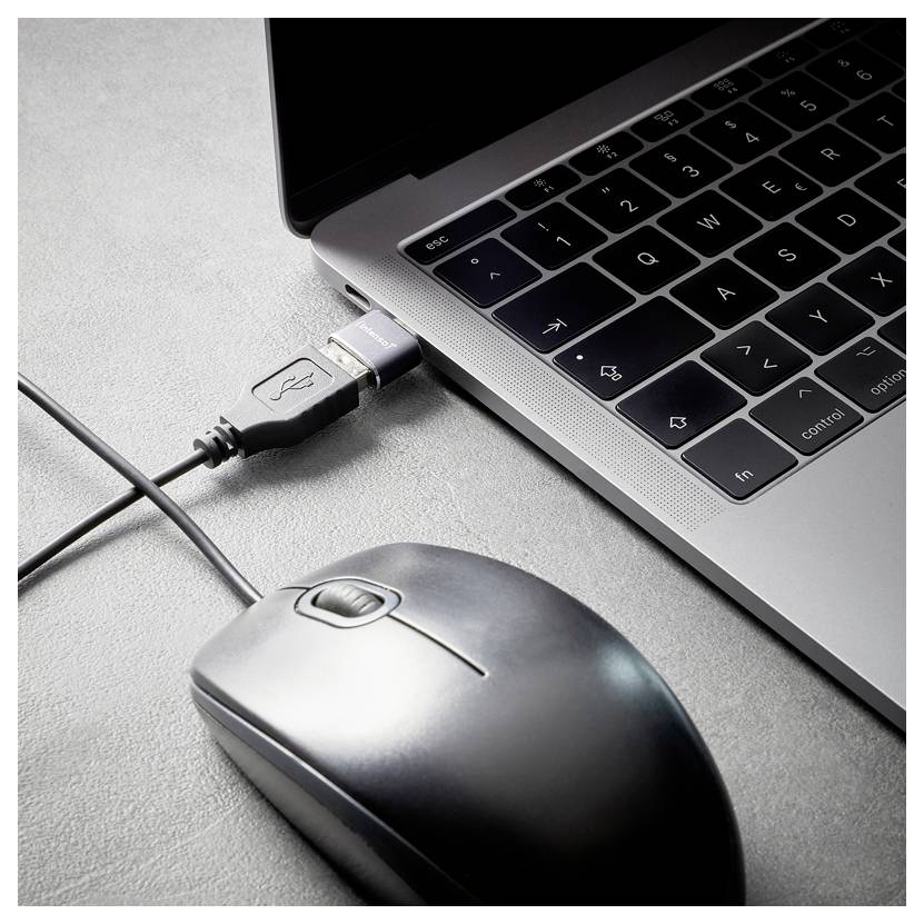Nahaufnahme eines Laptops mit einem eingesteckten USB-Kabel und einer Computermaus daneben auf einem grauen Schreibtisch.