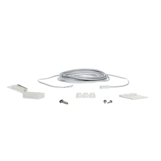 Kit mit aufgerolltem weißem Kabel mit Anschlüssen, Schrauben, Montageklötzen und einer kleinen weißen Platte auf einfachem Hintergrund.