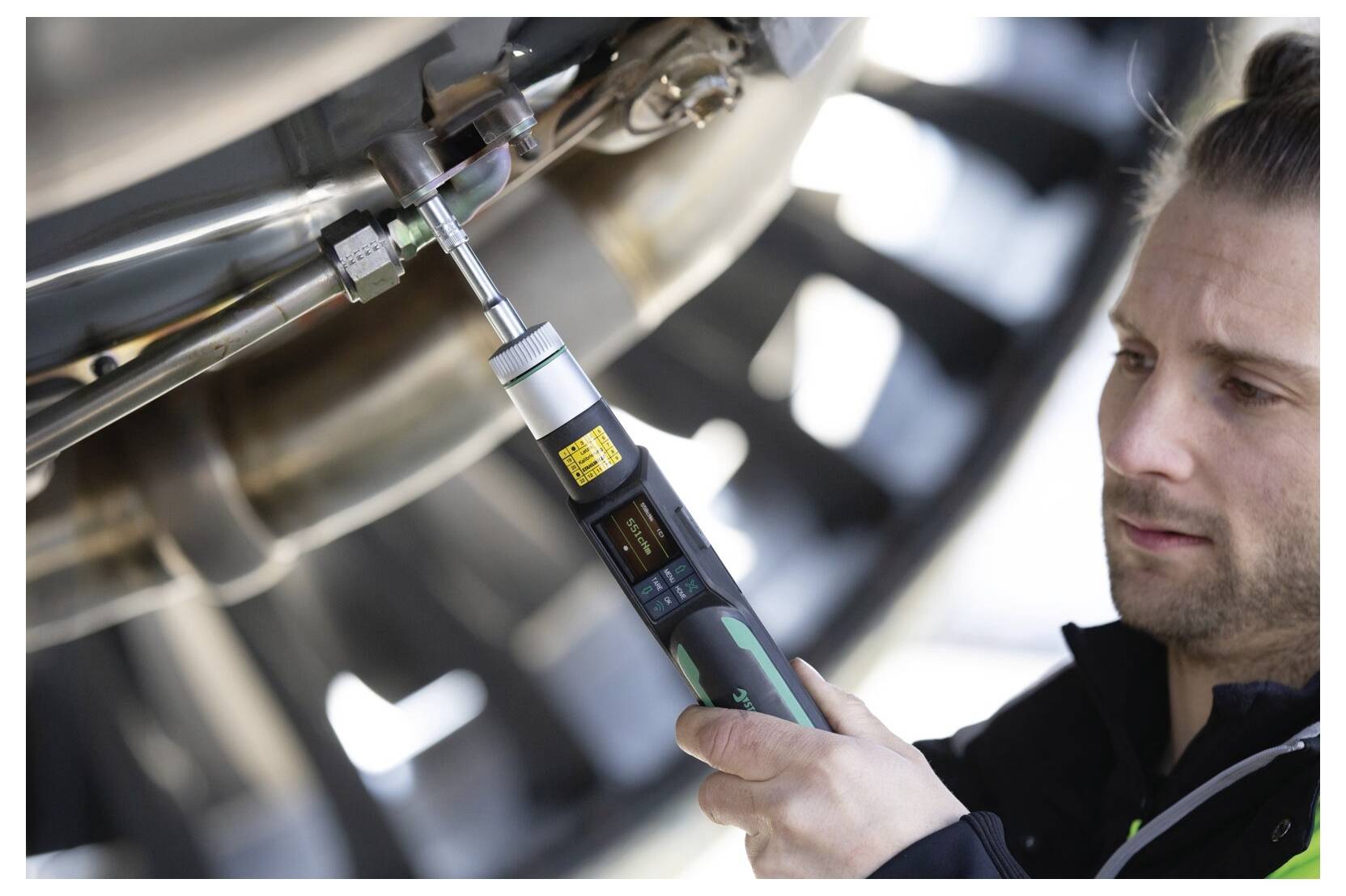 Techniker zieht eine Verbindung an einer Industriemaschine mit einem tragbaren Drehmoment-Werkzeug während einer Wartungsprüfung an.