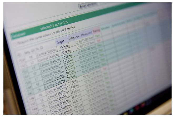 Unscharfe Nahaufnahme eines Computerbildschirms mit einer Inspektionsdatentabelle, auf der oben „5 von 134 ausgewählt" angezeigt wird und Zeilen mit Zielwerten, Toleranzen und gemessenen Werten.