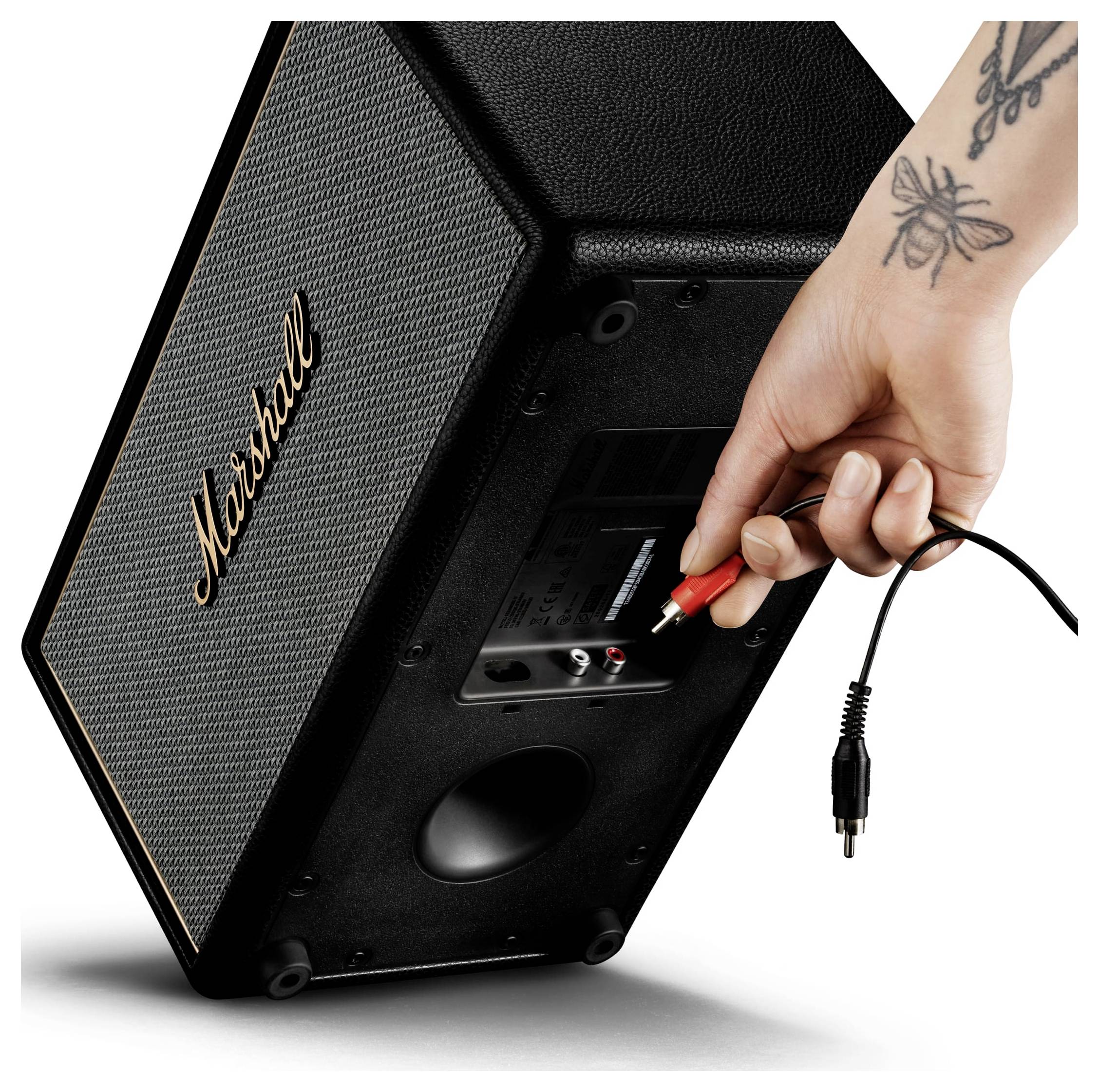 Hand steckt ein Audiokabel in die Rückseite eines Marshall-Lautsprechers oder -Verstärkers und zeigt sein Eingangspanel und die Stromversorgungsverbindung.