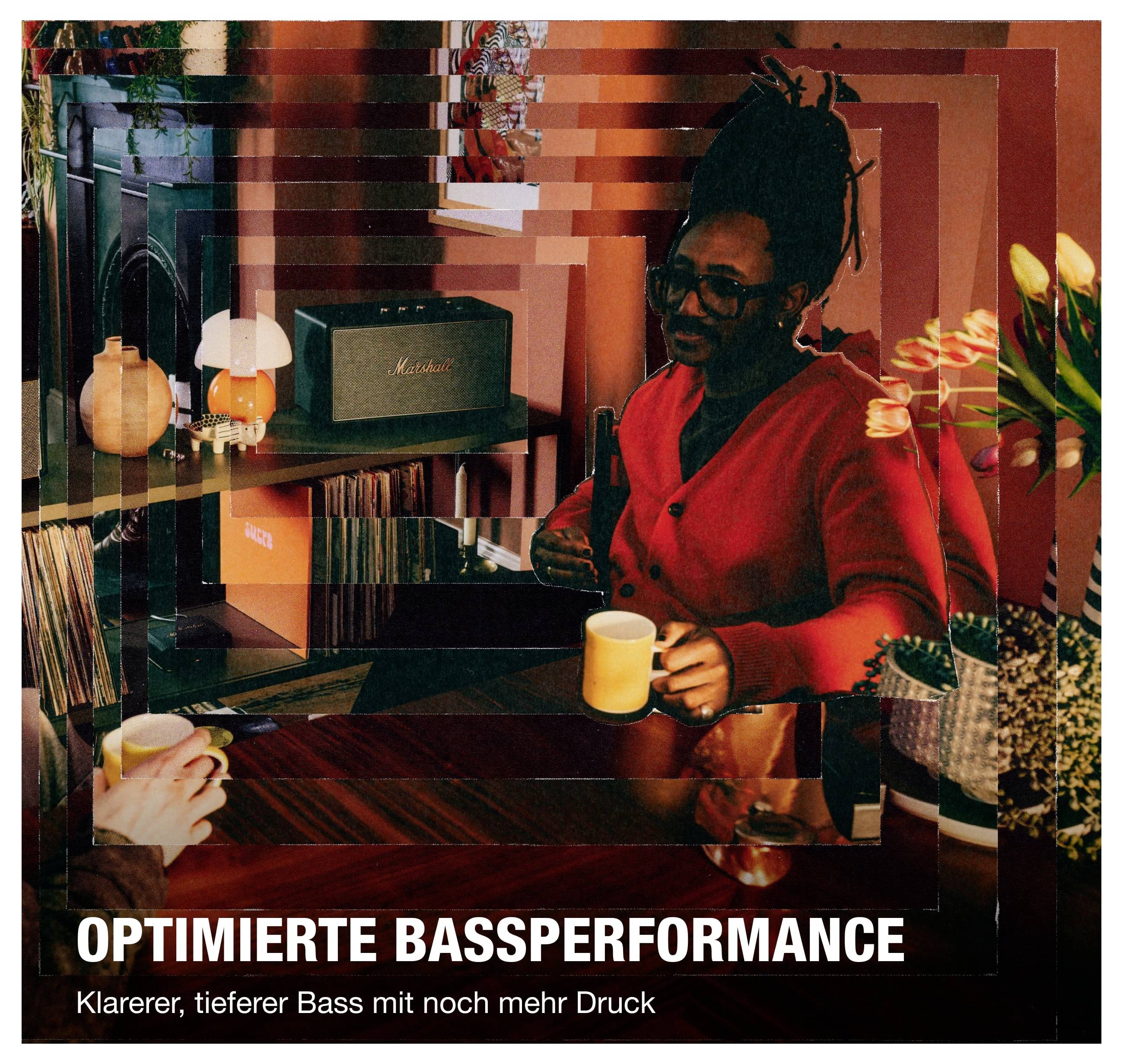 Werbung mit Frau im roten Pullover in einem Raum; unten der Text 'OPTIMIERTE BASSPERFORMANCE' und 'Klarerer, tieferer Bass mit noch mehr Druck'.