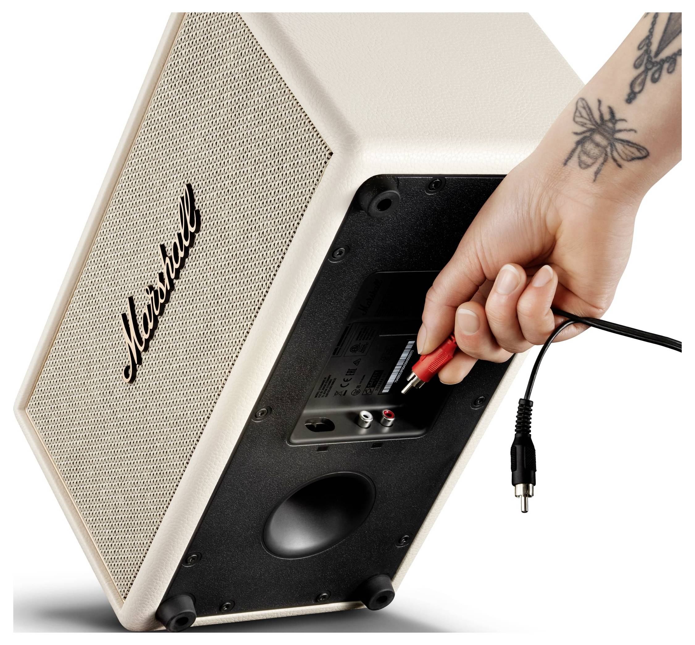 Die Hand steckt ein Kabel in die Rückseite eines Marshall-Lautsprechers oder -Verstärkers.