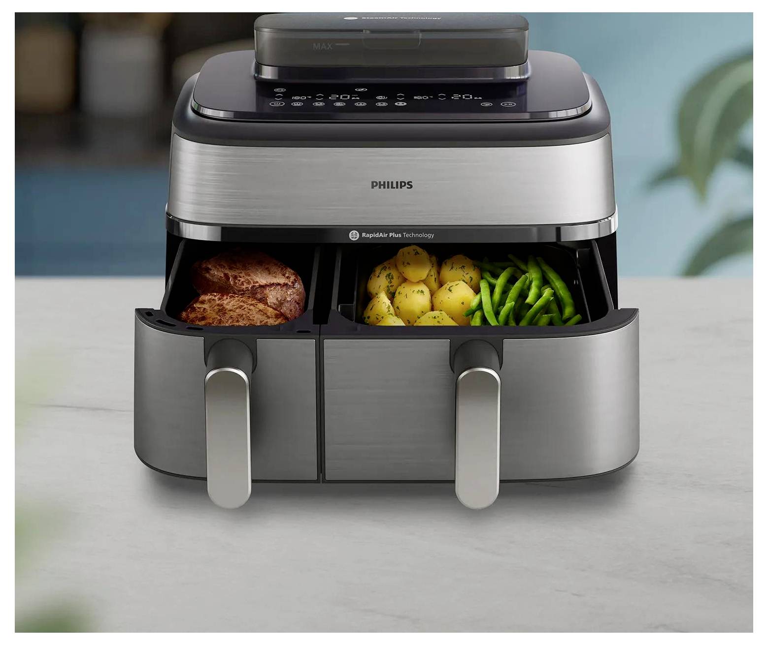 Philips Doppelschublade-Heißluftfritteuse auf einer Küchenarbeitsfläche, wobei eine Schublade einen Braten und die andere Kartoffeln und grüne Bohnen enthält.