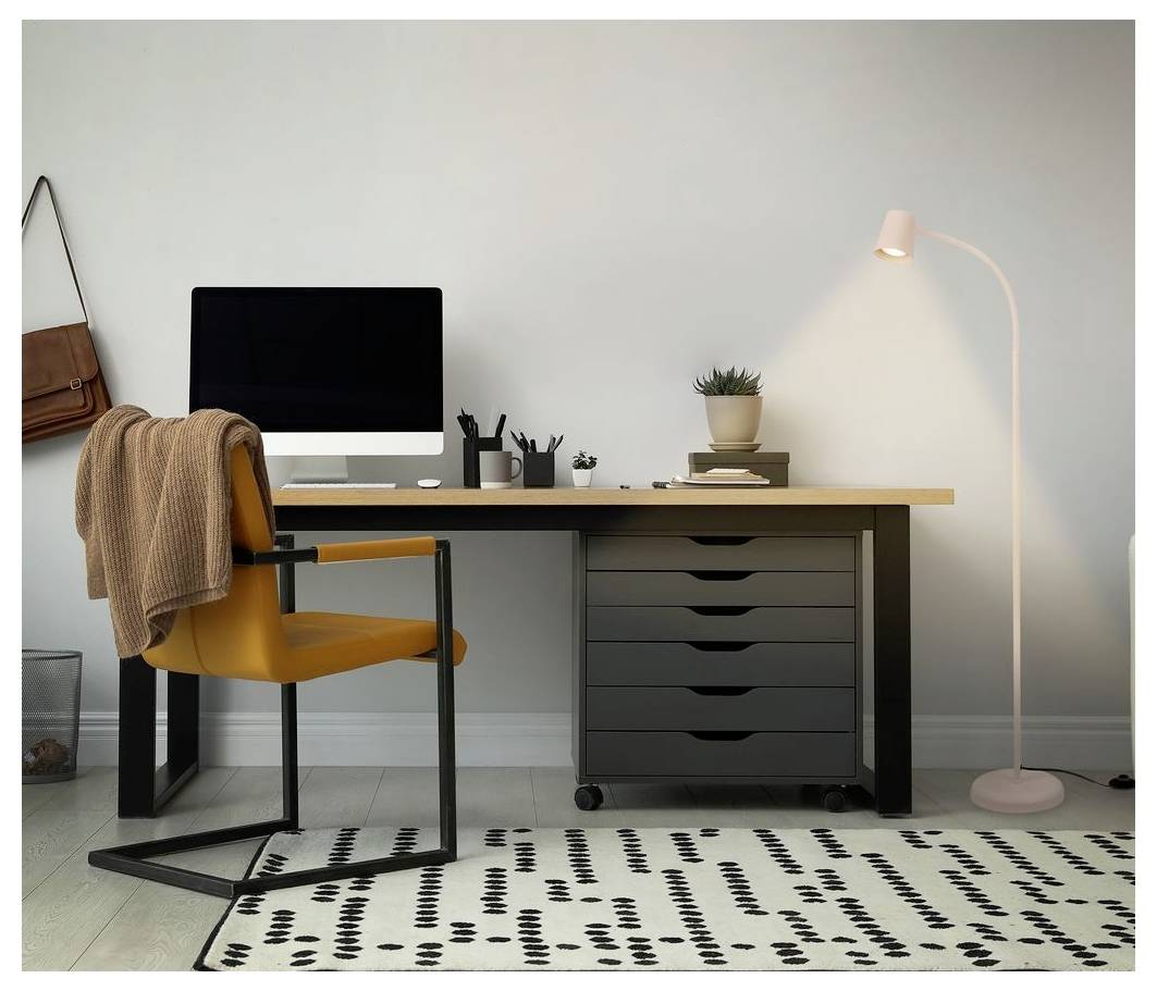 Minimales Homeoffice mit Schreibtisch, Computer, Senfstuhl, Schubladen, Stehlampe und gemustertem Teppich an einer schlichten Wand.