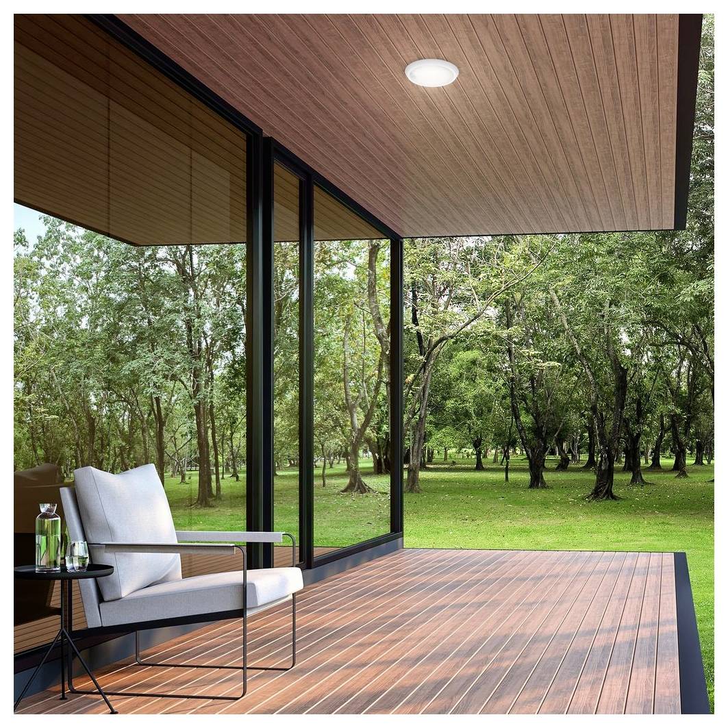 Moderne überdachte Terrasse mit einem weißen Stuhl und einem Beistelltisch mit Blick auf einen grünen Waldgarten.