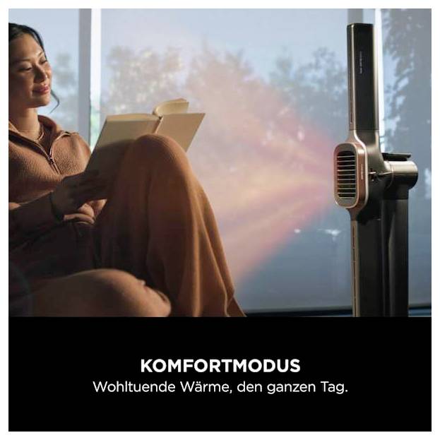 # Frau liest neben einem Turmheizer; der Anzeigentext sagt „KOMFORTMODUS" und „Wohltuende Wärme, den ganzen Tag."