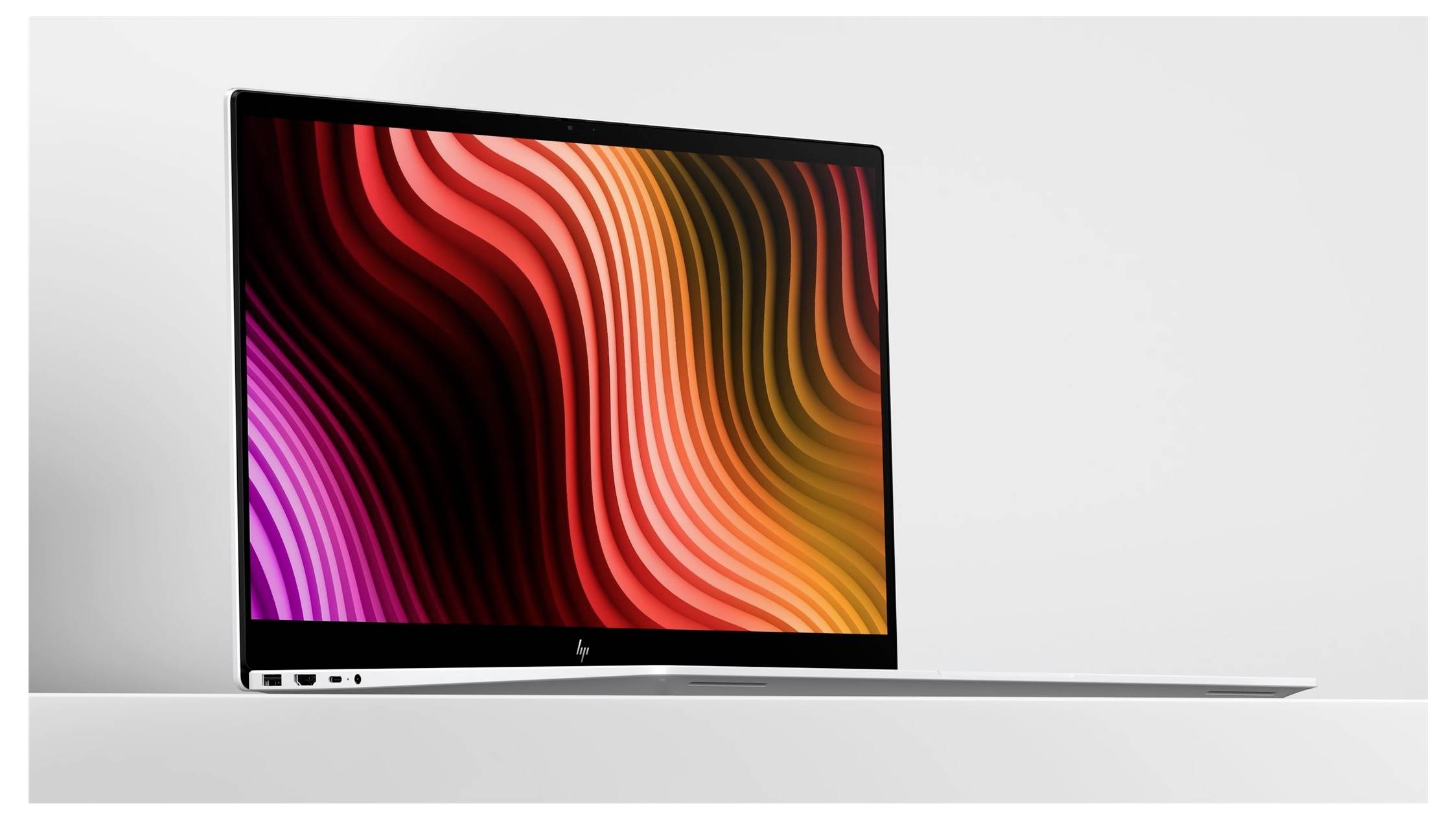 Silberner Laptop in Seitenansicht, aufgeklappt mit einem farbenfrohen abstrakten Wellenmuster in Rot, Orange und Rosa auf dem Bildschirm.