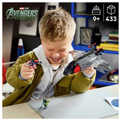 Lächelnder Junge spielt mit Avengers LEGO-Set, hält eine Captain America-Minifigur und einen grauen Jet; das Etikett zeigt '9+' und '433' Teile.