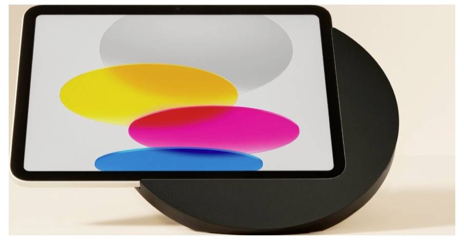 Ein Tablet mit leerem Bildschirm, das auf einem dunklen kreisförmigen Ständer steht und überlappende gelbe, rosa und blaue Ovale zeigt.
