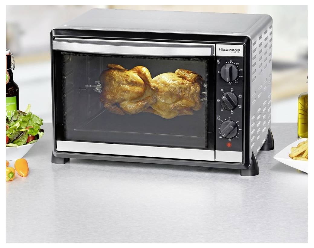Elektrogrill-Rotisserieofen auf der Arbeitsplatte mit einem ganzen Hähnchen, das darin auf einer Küchencounter brät.