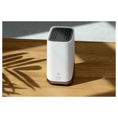 Weiße eufy Security Haushaltsicherheitskamera, die auf einem Holztisch in der Sonne steht und einen langen Schatten wirft.