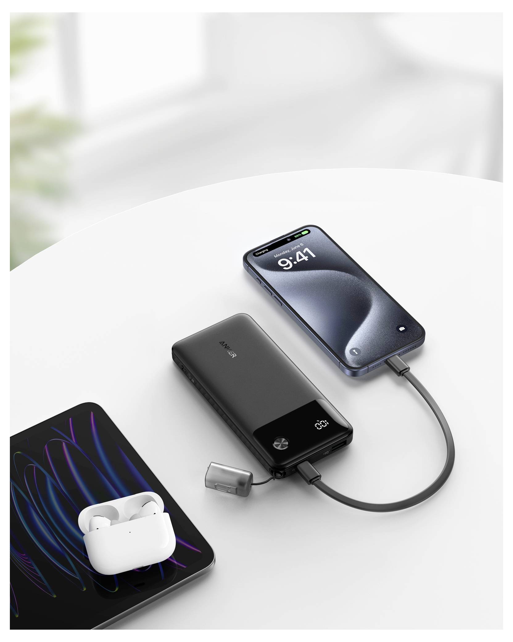 Ein Smartphone lädt eine tragbare Powerbank auf, die gleichzeitig kabellose Kopfhörer auf einem Tablet auflädt.