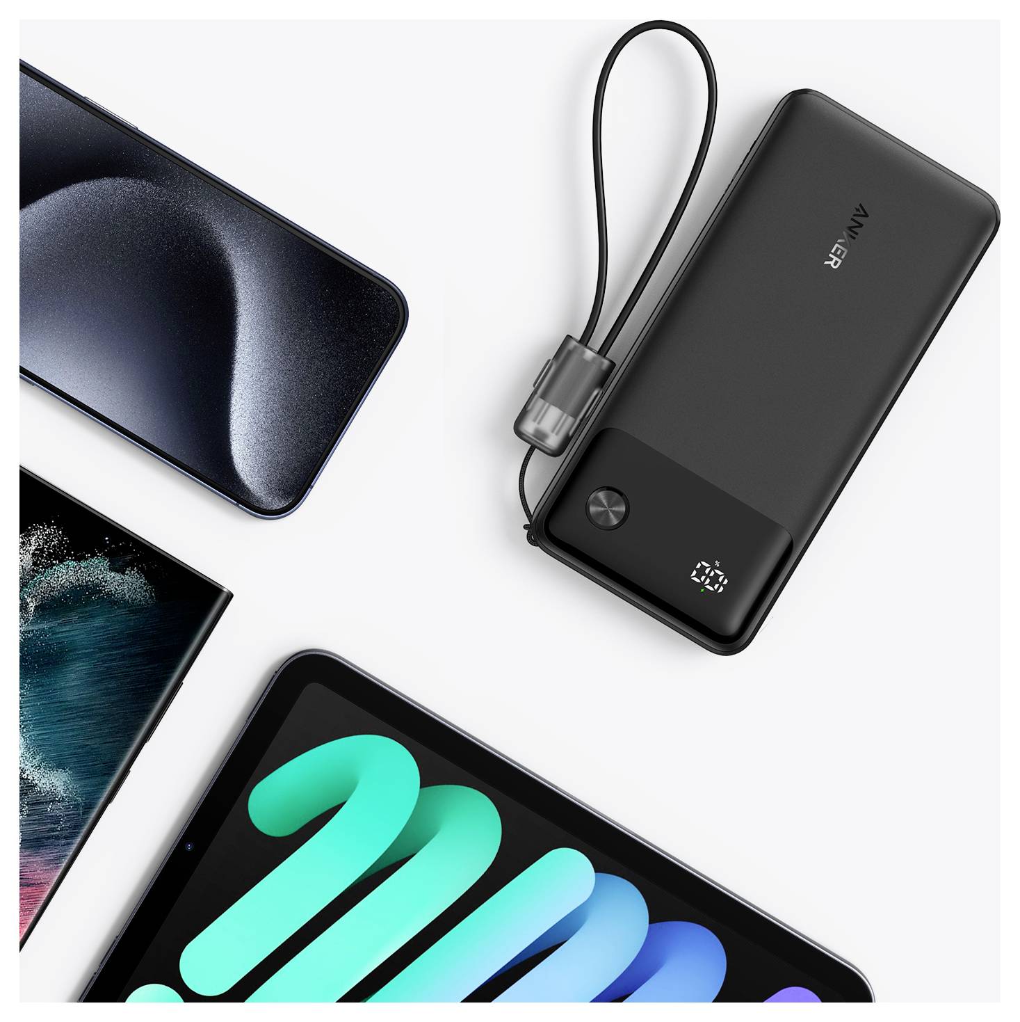 Draufsicht-Produktfoto einer schwarzen Anker-Powerbank mit Handschlaufe neben teilweisen Smartphone-Bildschirmen auf weißem Hintergrund.