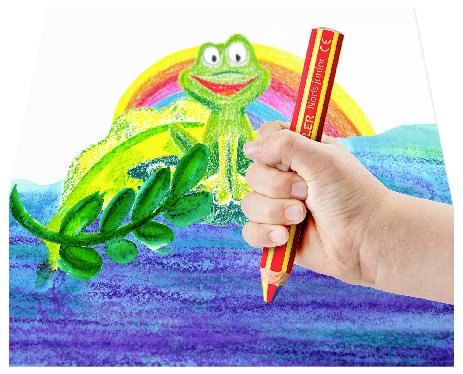 Eine Hand, die einen roten Bleistift hält, zeichnet über einer farbenfrohen, kindlichen Szene mit einem lächelnden Frosch, einem Regenbogen, blauem Wasser und grünen Blättern.