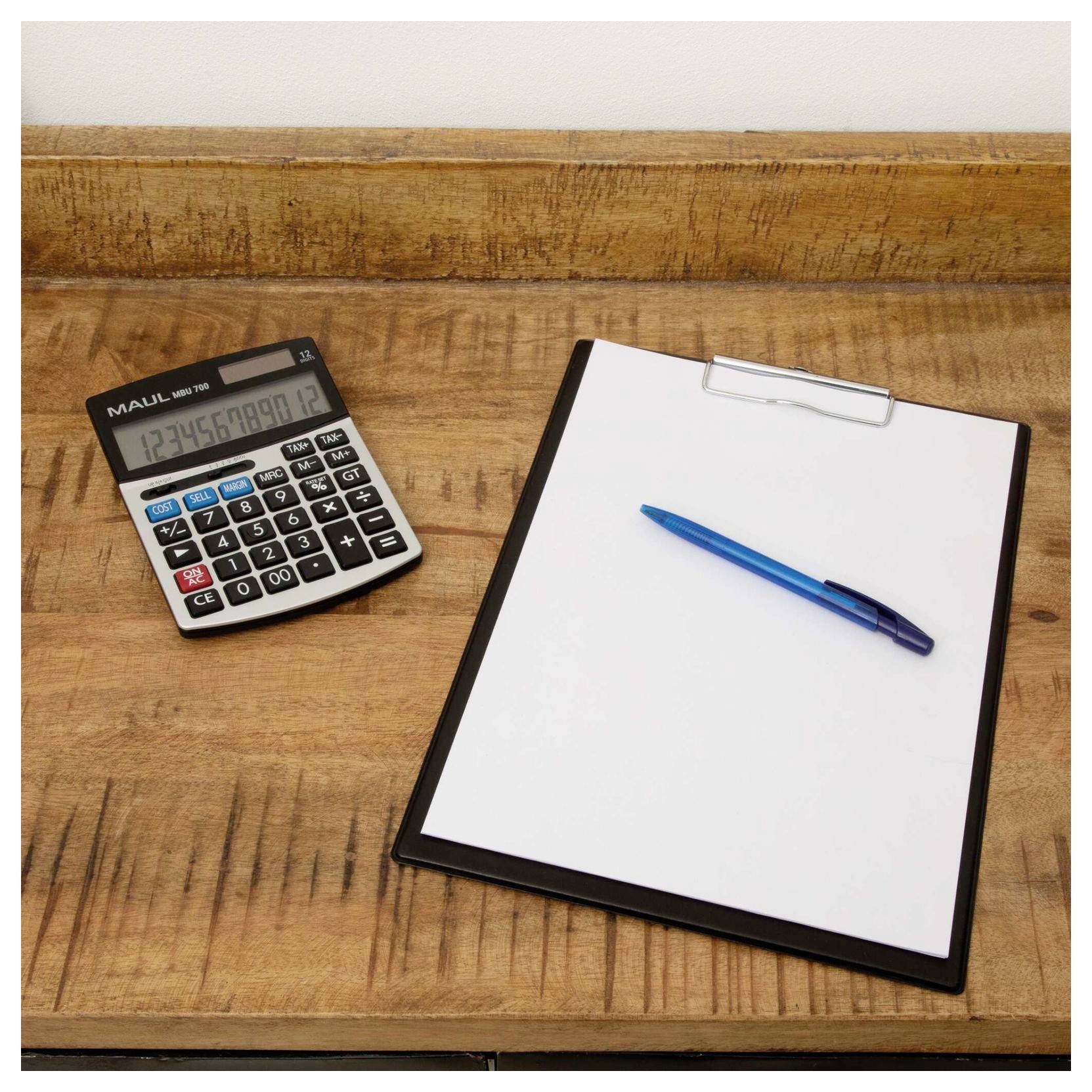 Taschenrechner neben einer Zwischenablage mit leerem Papier und einem blauen Stift auf einem Holzschreibtisch.
