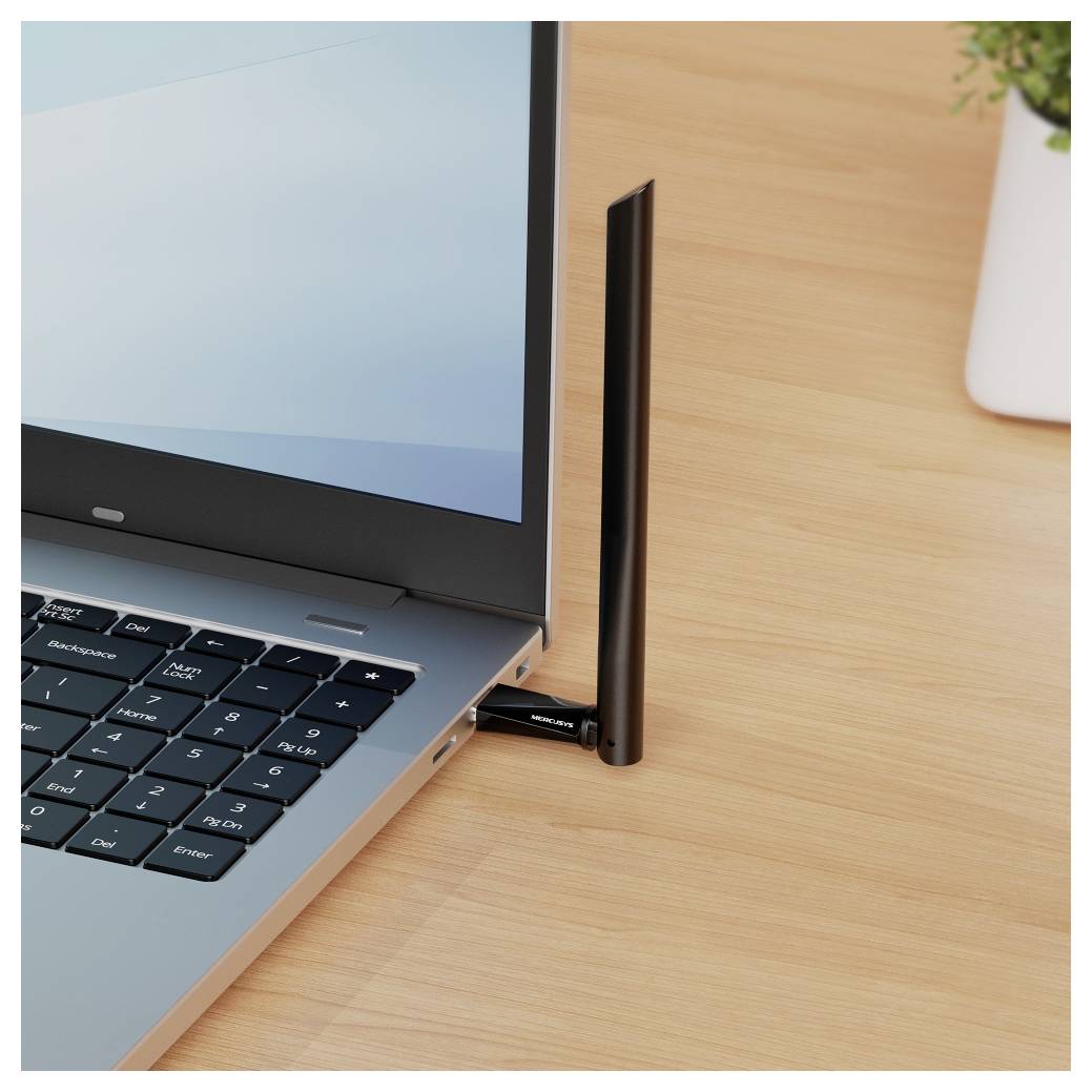 Laptop mit einer in die Seite eingesteckten USB-WLAN-Antenne, aufrecht auf einem Holzschreibtisch stehend.