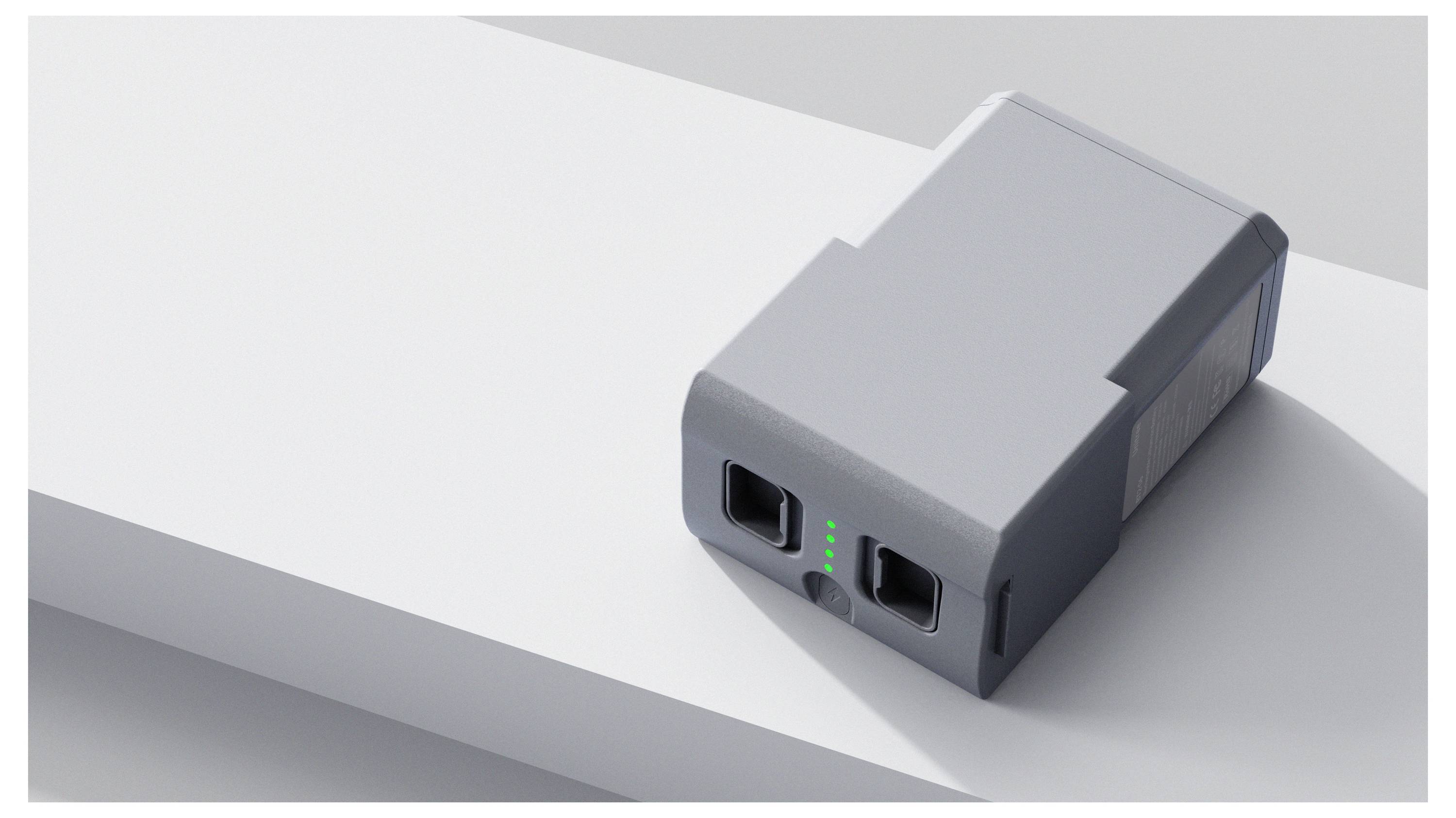 Kompakter grauer Dual-Port-Stromadapter auf weißer Oberfläche mit grünen LED-Indikatoren und schrägemSchatten.