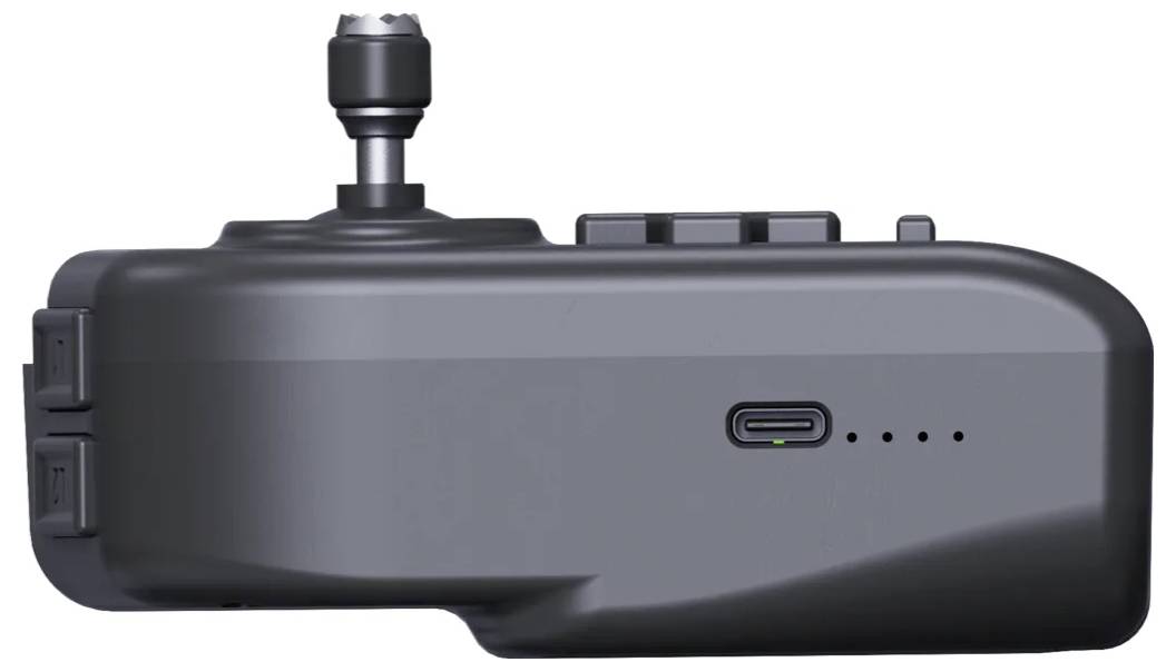 Seitenansicht eines kompakten dunkelgrauen Geräts mit einem oben angebrachten Drehknopf, USB-C-Anschluss, Batterieanzeigeleuchten und seitlichen Verriegelungsknöpfen.
