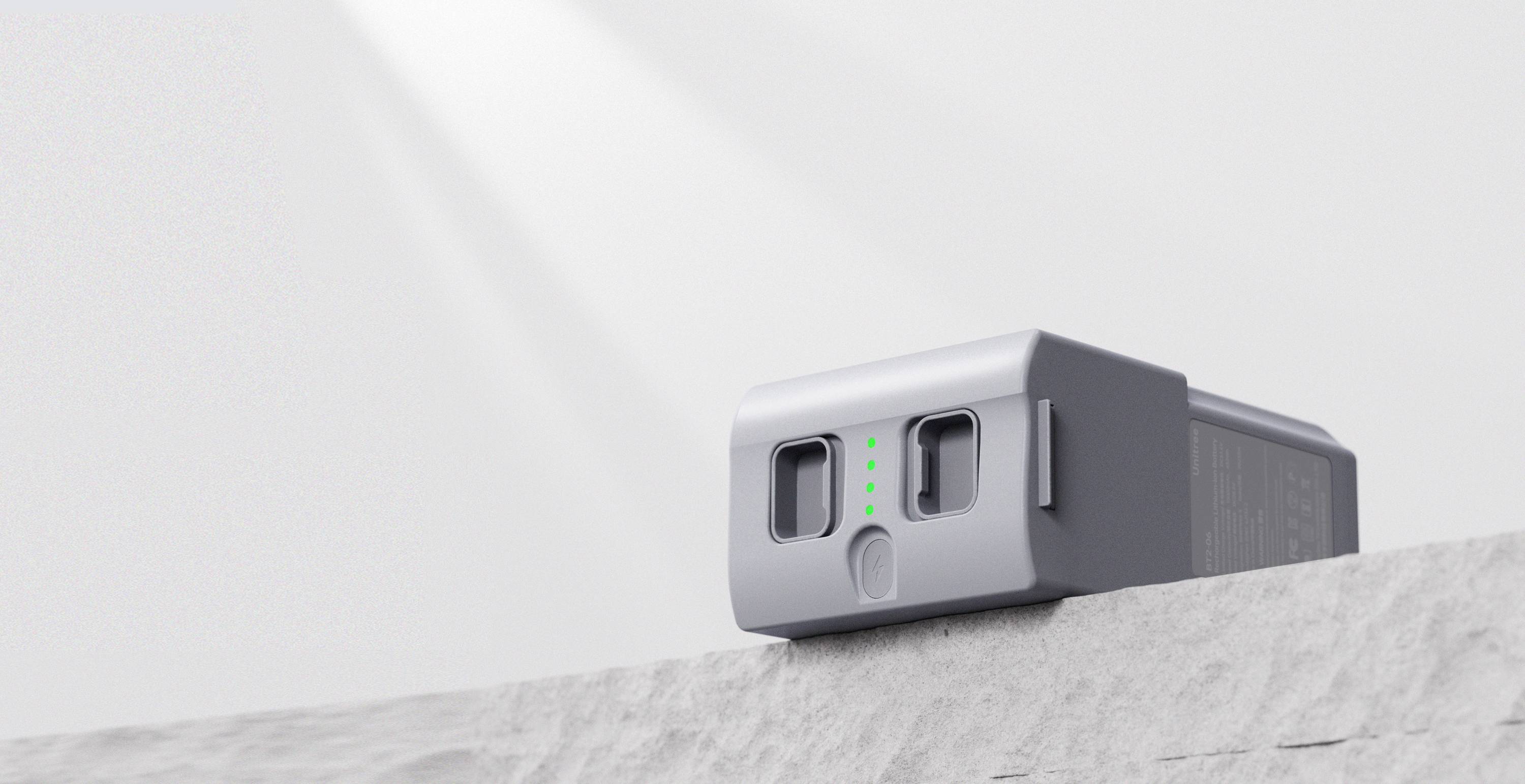 Kleines graues elektronisches Gerät mit zwei vorderen Öffnungen und grünen Kontrollleuchten, das auf einem Sims oder Dach vor einem hellen Himmel sitzt.