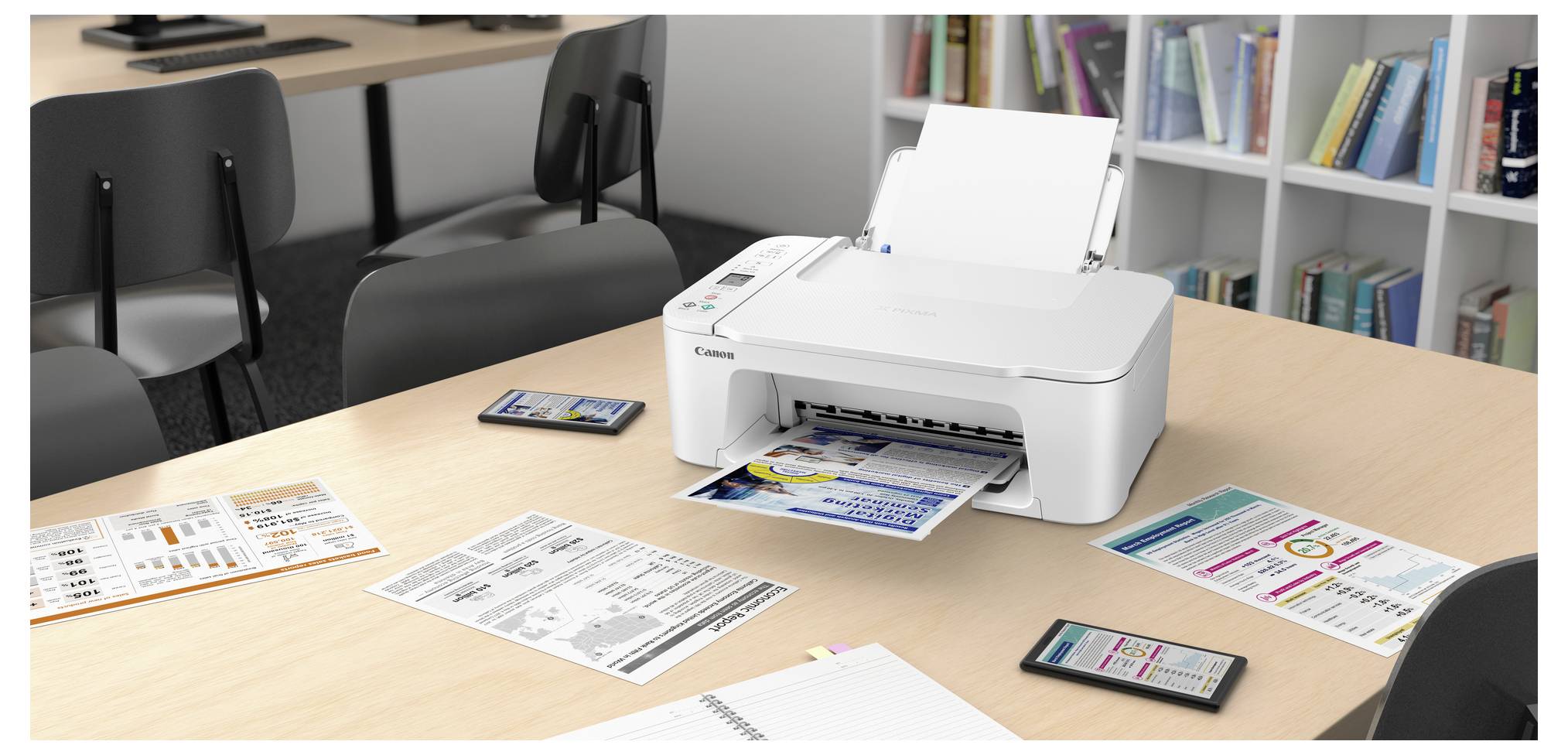 Weißer Canon-Drucker auf einem Schreibtisch, der ein farbiges Flugblatt druckt, umgeben von Diagrammen und Smartphones in einem Konferenzraum im Büro.
