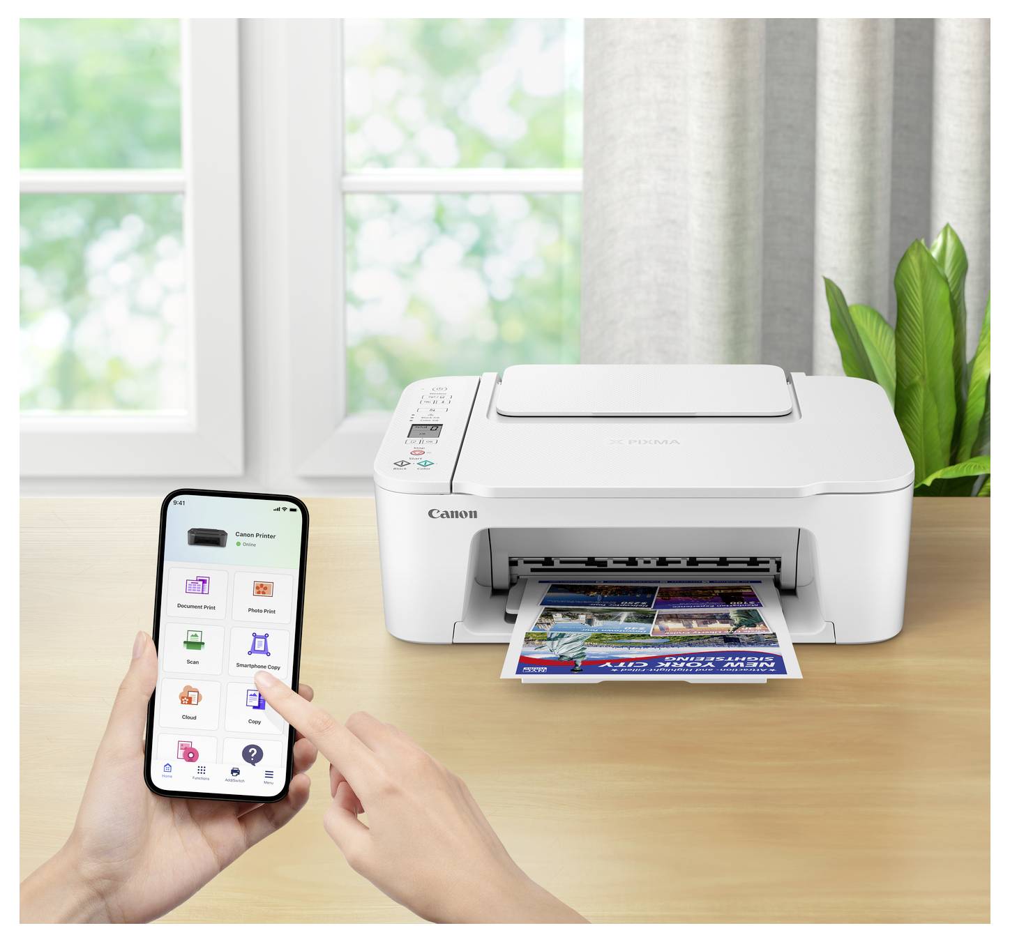 Eine Person nutzt eine Smartphone-App, um einen Canon-Drucker zu steuern, der ein farbiges Dokument auf einem Schreibtisch neben einem Fenster druckt.