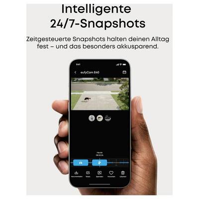 Smartphone-App-Bildschirm für eufyCam E40 mit einem 24/7-Schnappschuss einer Einfahrt mit einem Hund; deutscher Text bewirbt zeitgesteuerte Schnappschüsse und Batterieeinsparungen.