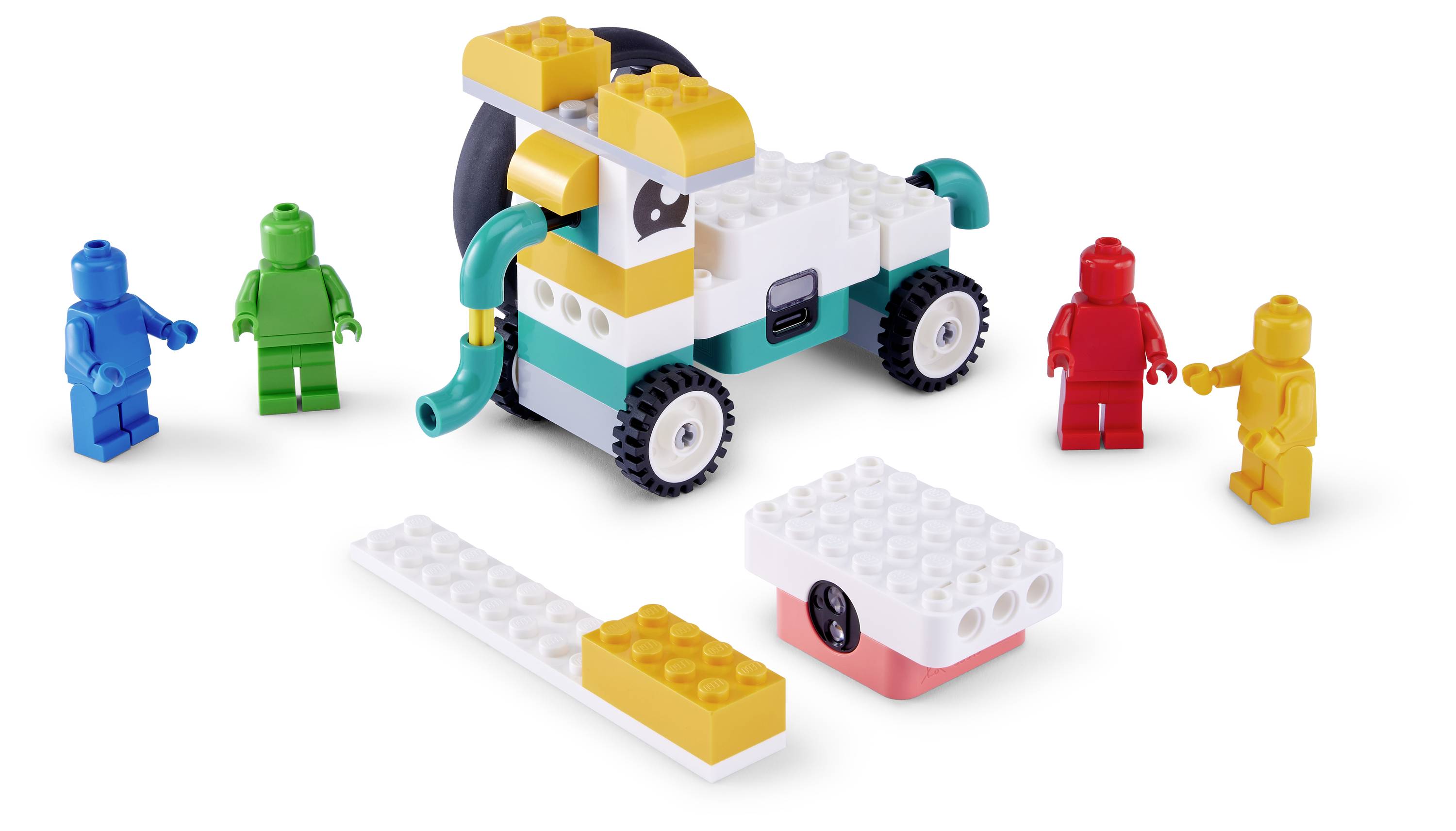 LEGO-ähnlicher Spielzeugauto-Bausatz mit blauen, grünen, roten und gelben Minifiguren, die darum herum stehen, plus lose Steine und einem weiß-rosa Block auf weißem Hintergrund.