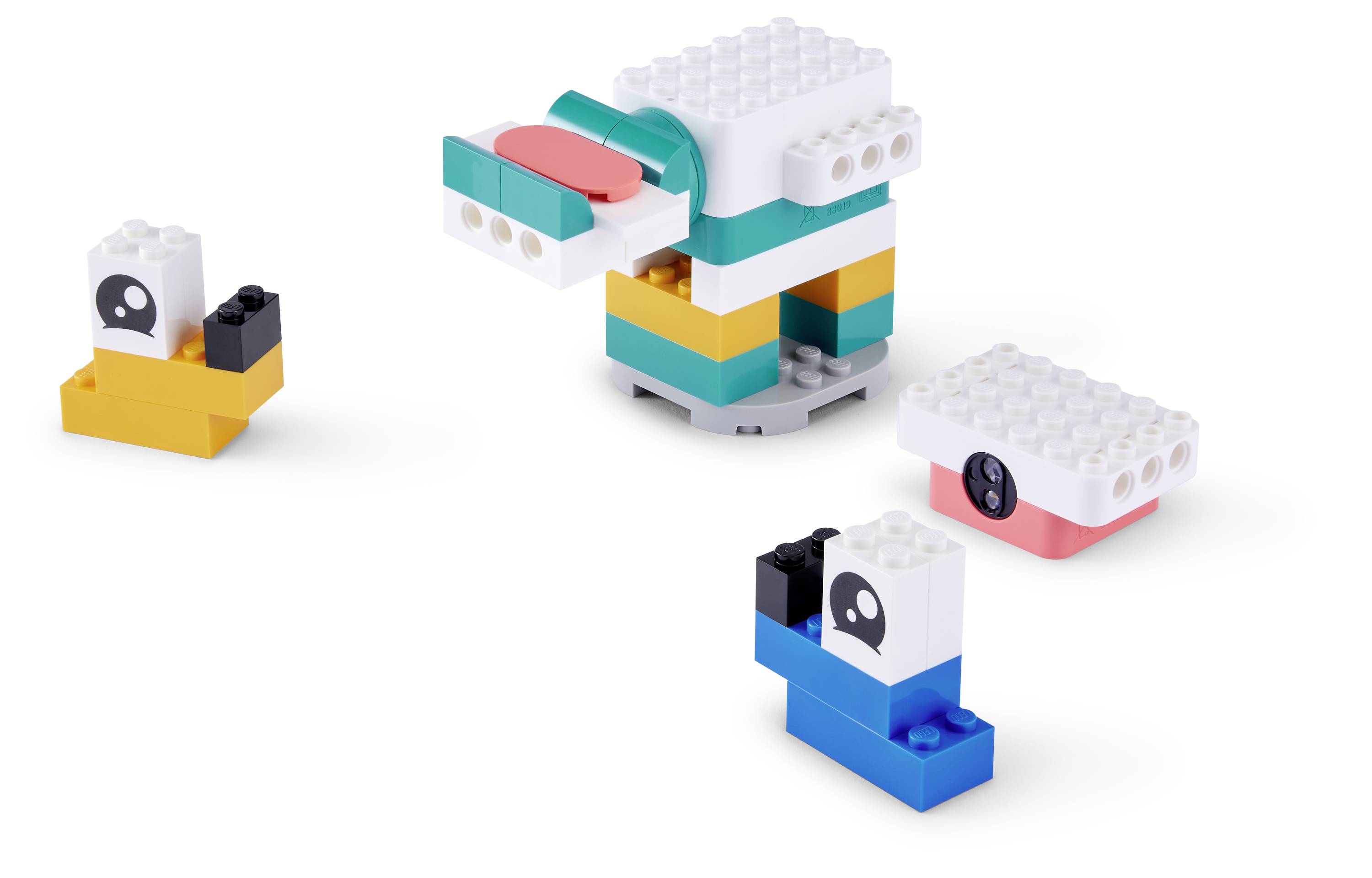 Drei kleine LEGO-ähnliche, aus Blöcken gebaute Roboterfiguren in Weiß, Blaugrün, Gelb, Blau und Schwarz, die auf weißem Hintergrund angezeigt werden.