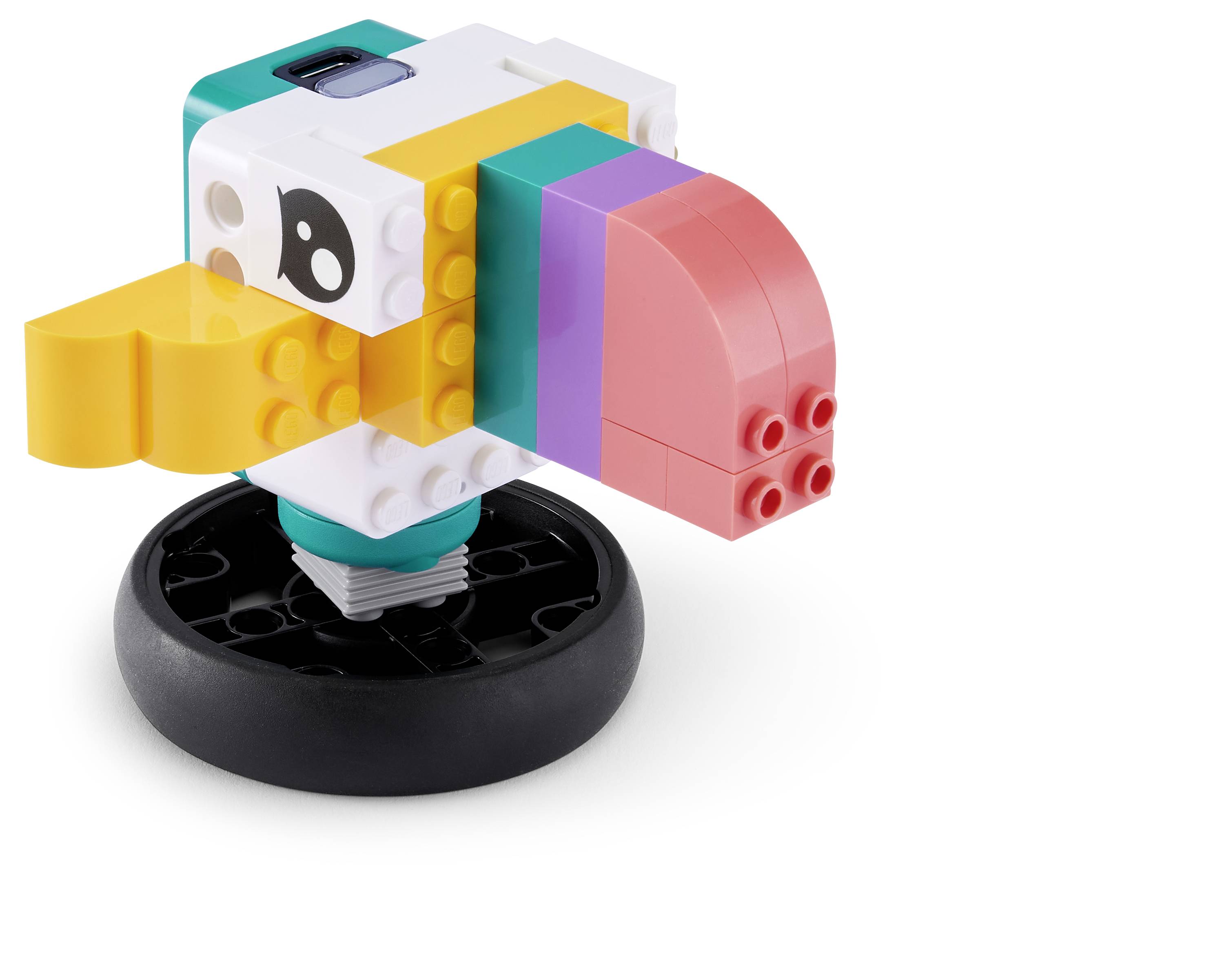 Ein buntes LEGO-ähnliches Vogelmodell auf einer schwarzen Basis, von der Seite gezeigt mit gelbem Schnabel, rosa Kopf und türkis-, weiß- und purpurfarbenen Körperblöcken.