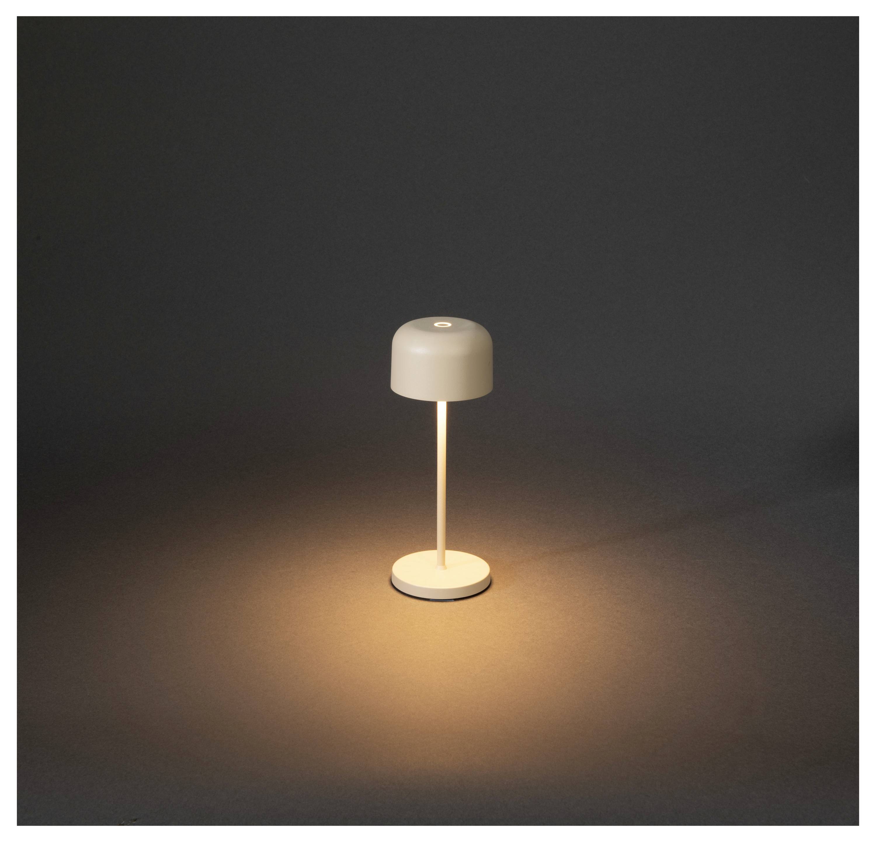 Eine kleine weiße Tischlampe wirft einen warmen, kreisförmigen Lichtkegel auf einen dunklen Hintergrund.