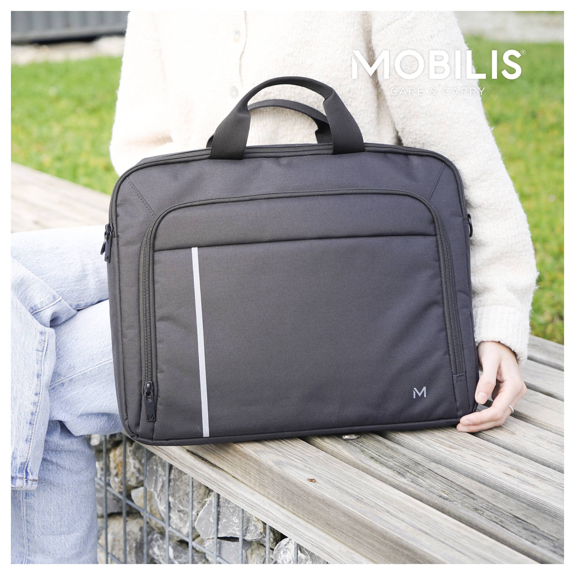 Person, die eine graue MOBILIS-Laptoptasche mit Griffen und vorderen Taschen hält, während sie auf einer Holzbank im Freien sitzt.
