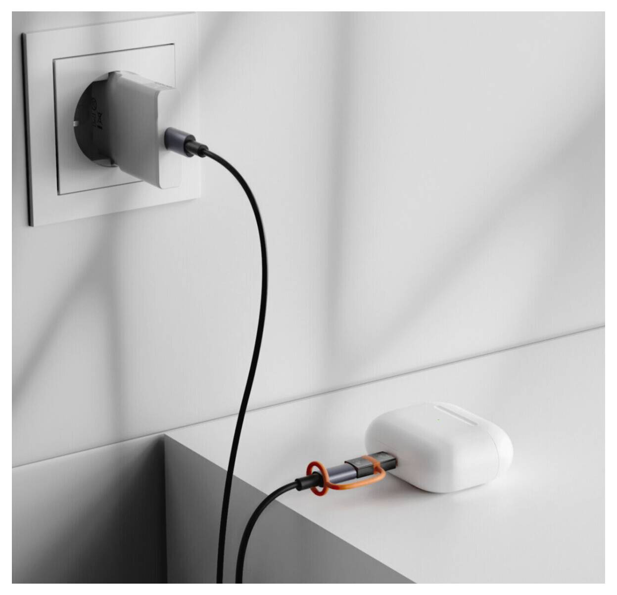 Stromkabel, die in eine Wandsteckdose gesteckt sind, und ein weißer Ladegerät auf einem Schreibtisch, die eine elektrische Ladeeinrichtung zeigen.