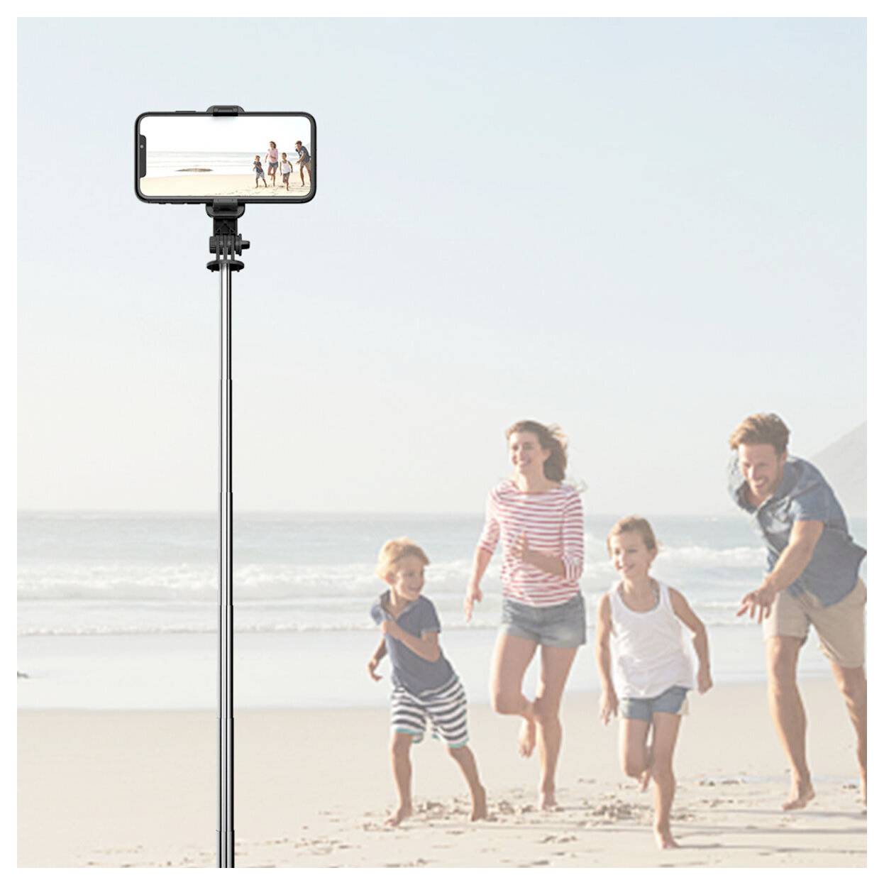 Eine Familie läuft am Strand, während sie mit einem Smartphone gefilmt wird, das auf einem hohen Stativ montiert ist.
