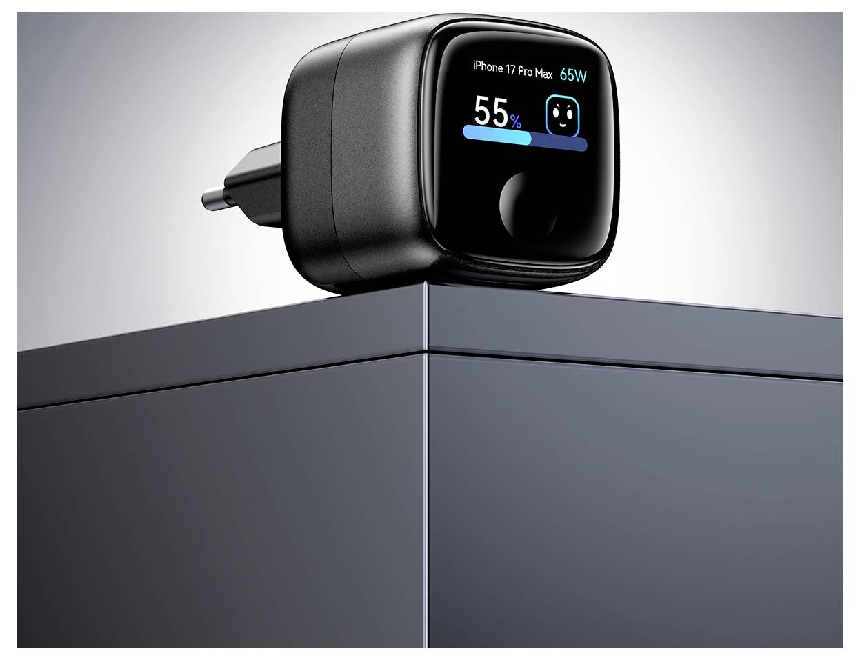 Schwarzes 65-W-Wandladegerät auf einer Box, mit Vorderbildschirm mit der Anzeige "iPhone 17 Pro Max 65W" und 55% Batterieladung.
