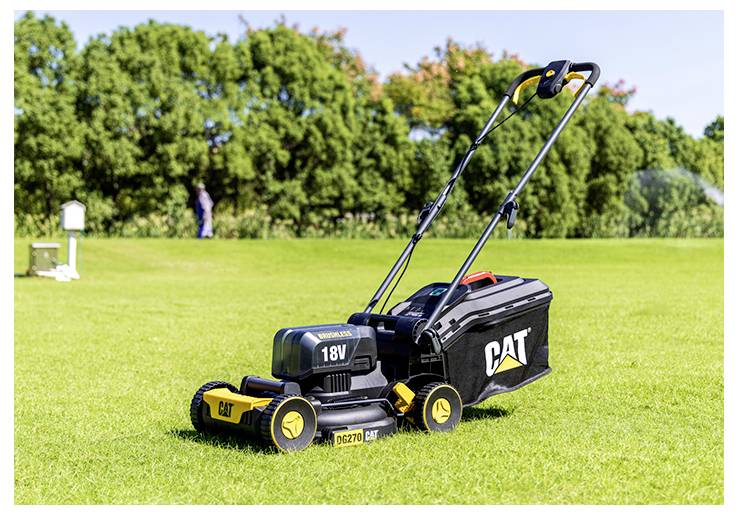 Batteriebetriebener CAT 18V Rasenmäher auf einer Grünfläche, mit Bäumen im Hintergrund.
