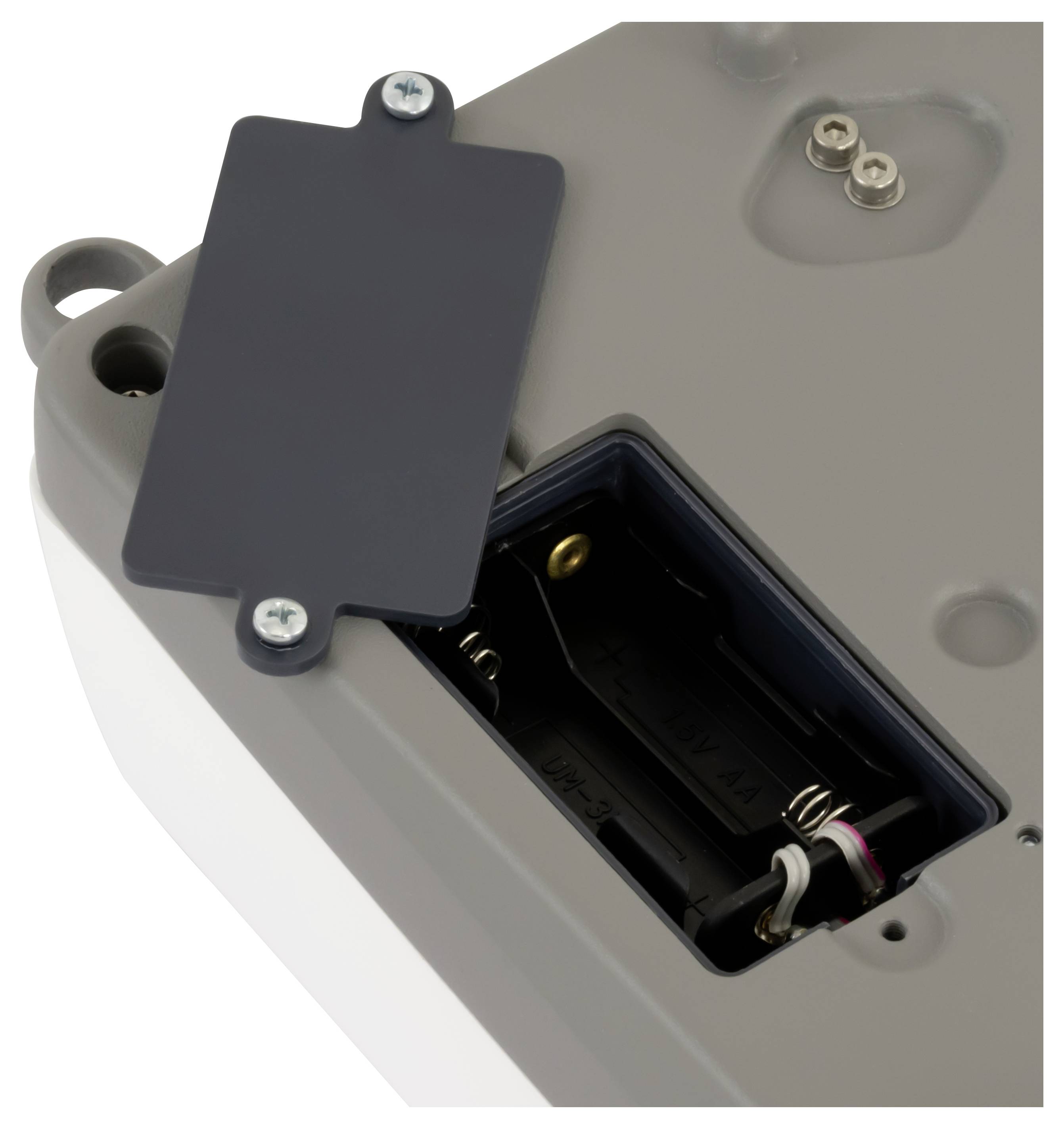 Nahaufnahme eines elektronischen Geräts mit geöffnetem Batteriefach, das Federn und Verkabelung unter einer dunklen Abdeckplatte zeigt.