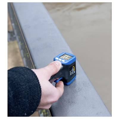 Tragbares digitales Messgerät, das die Oberfläche eines Brückengeländers neben Wasser misst.