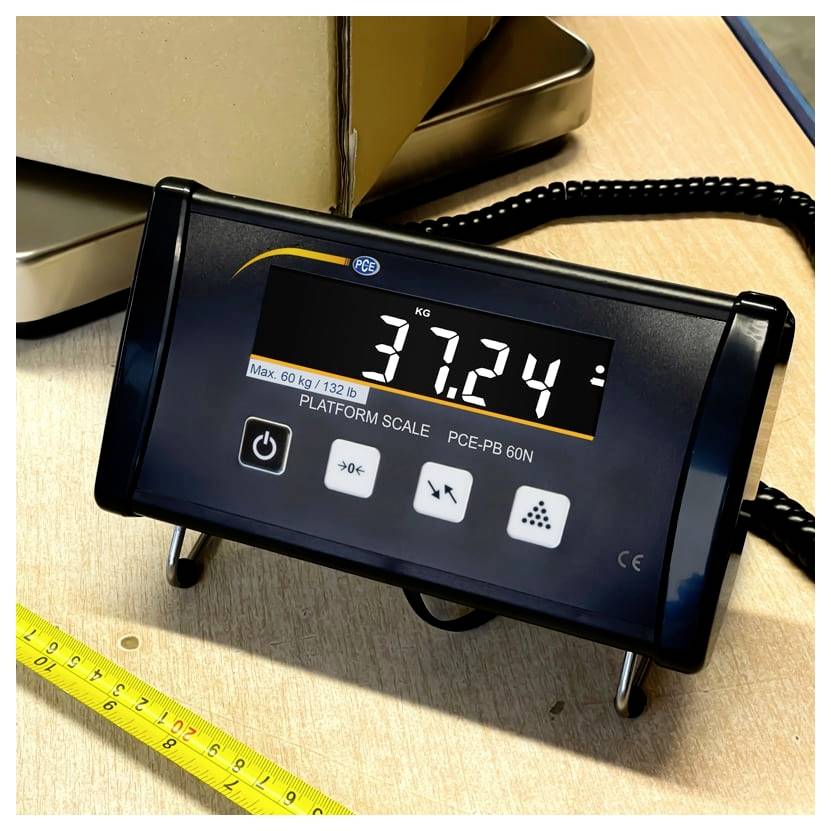 Digitale Plattformwaage zeigt 37,24 kg auf einer Tischplatte an, mit einem Messstab in der Nähe.