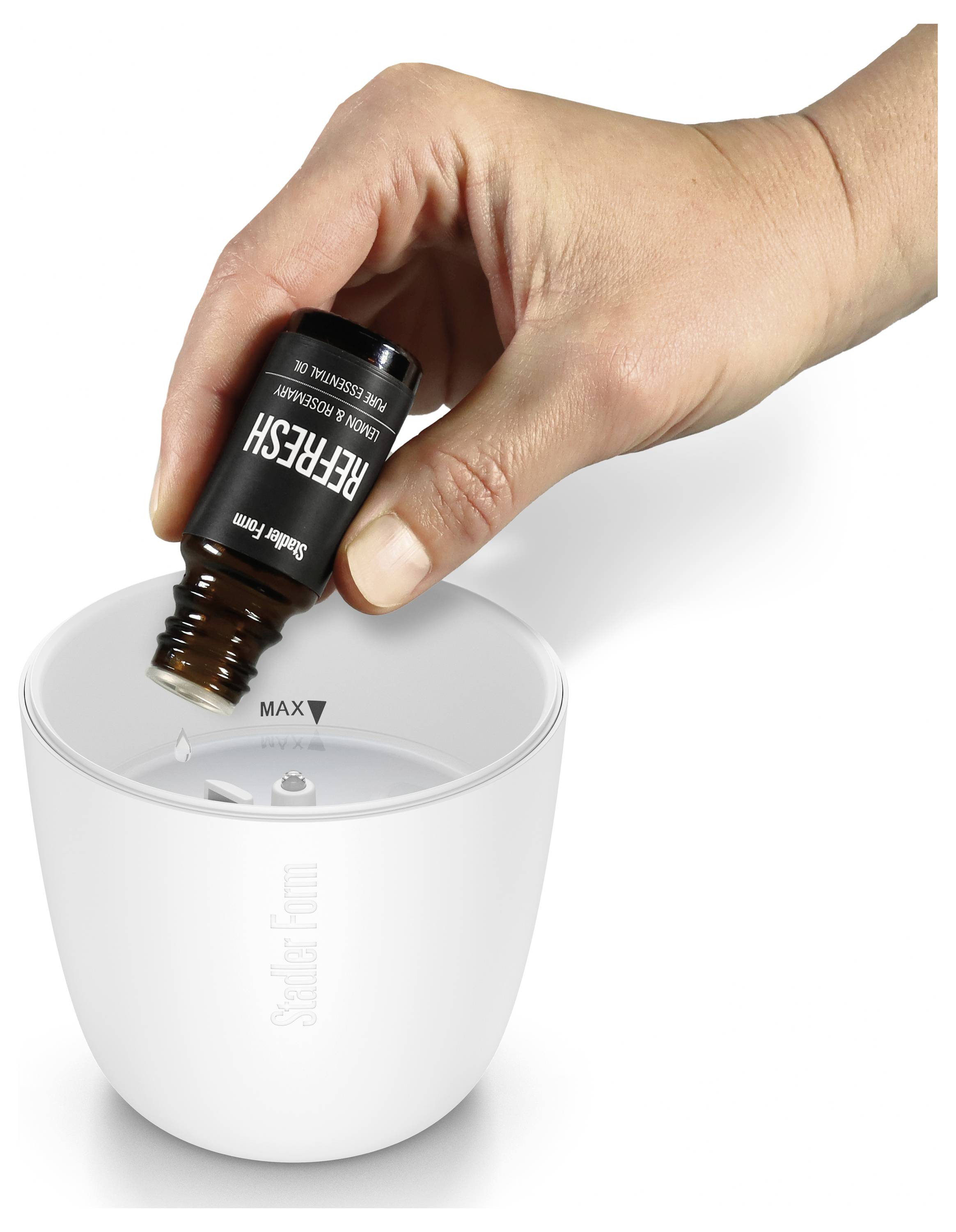 Hand gießt das ätherische Öl „Refresh" in einen weißen Saje-Diffuser und füllt ihn bis zur markierten MAX-Linie.