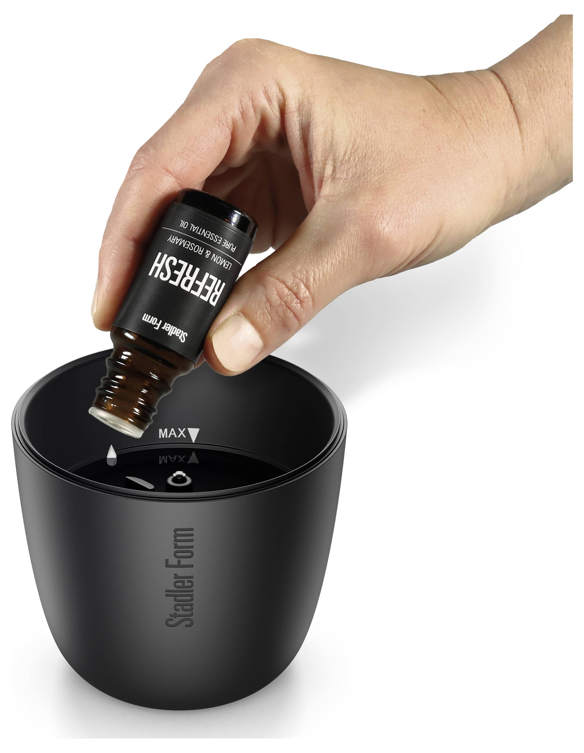 Hand gießt „Refresh"-Flüssigkeit aus einer kleinen Flasche in ein schwarzes Scalar Form-Gerät oder eine schwarze Tasse.