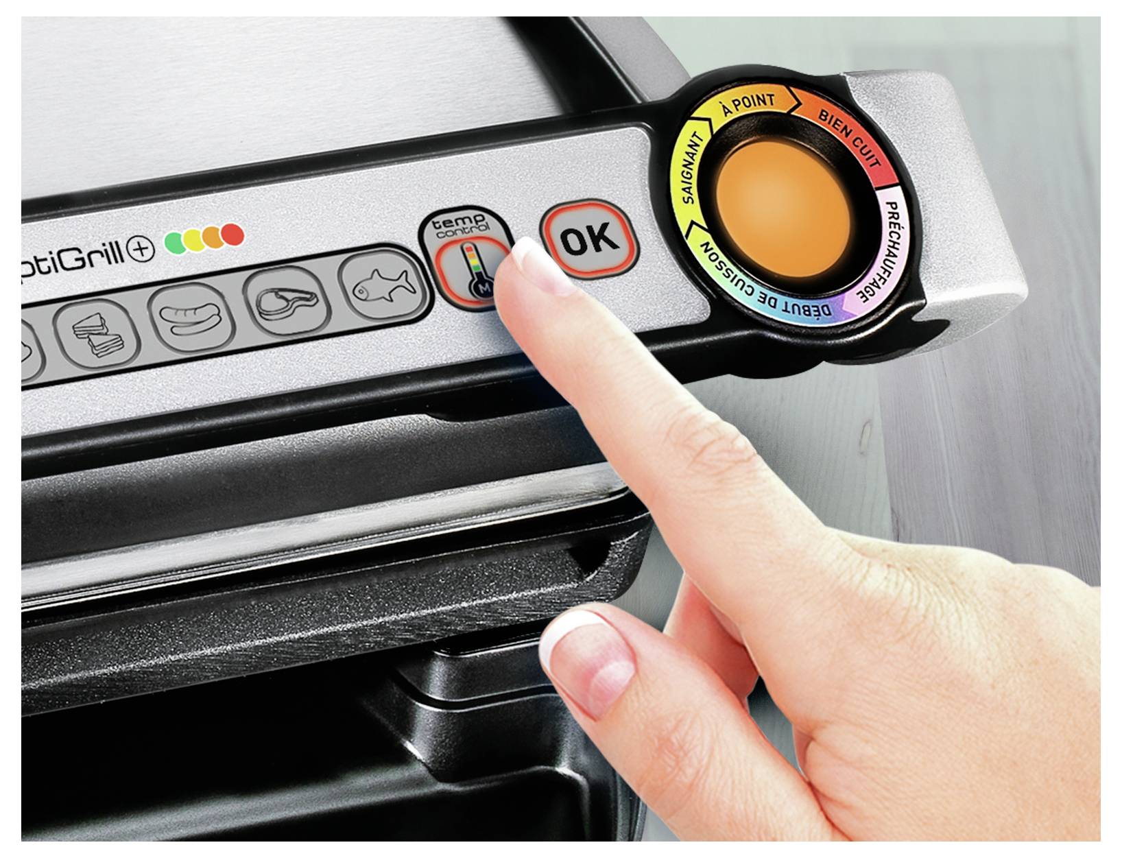 Finger drückt die Temperaturschaltfläche auf einem Tefal OptiGrill-Bedienfeld, mit sichtbaren Kochmodus-Symbolen und Gargrad-Skala.